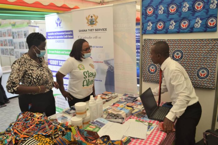 Officer of the Ghana TVET Service (in tie), explain a point to members of the public at the Service pavilion