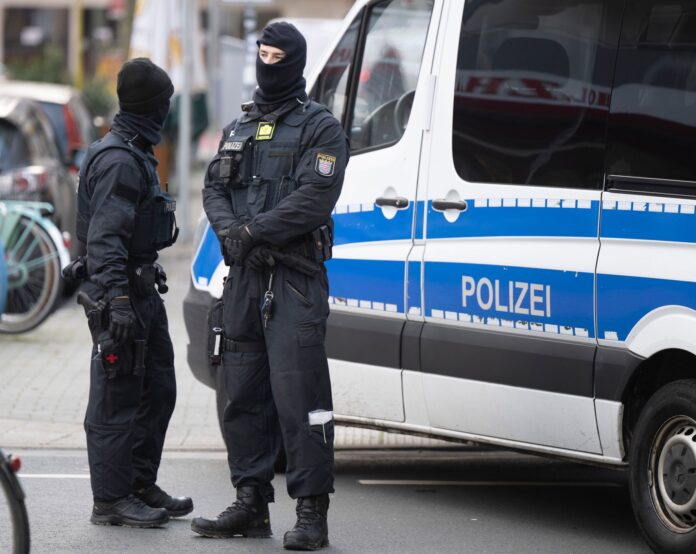 Police officers stand next to a searched property in Frankfurt during a raid against so-called 