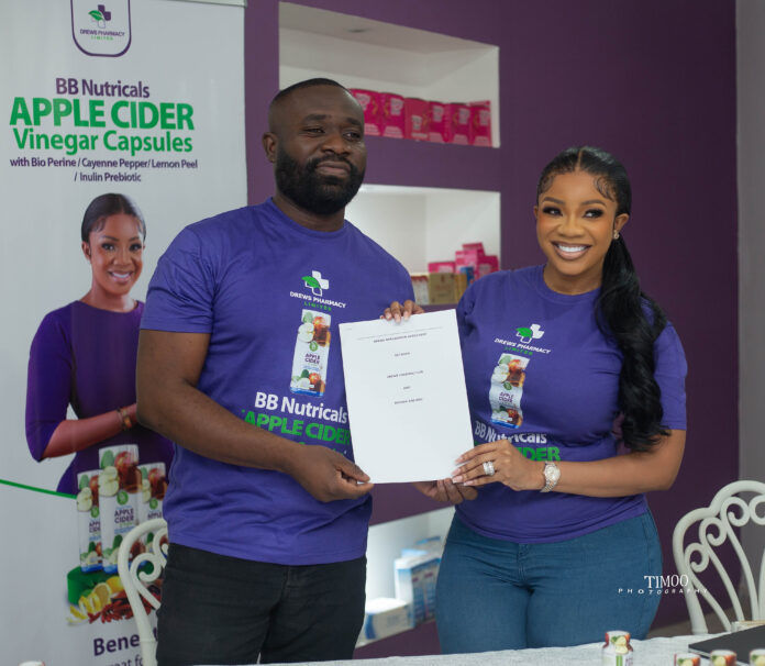 Andrew Kojo Kyere, Managing Director of Drews Pharmacy, left with Serwaa Amihere, right, with the agreement signed